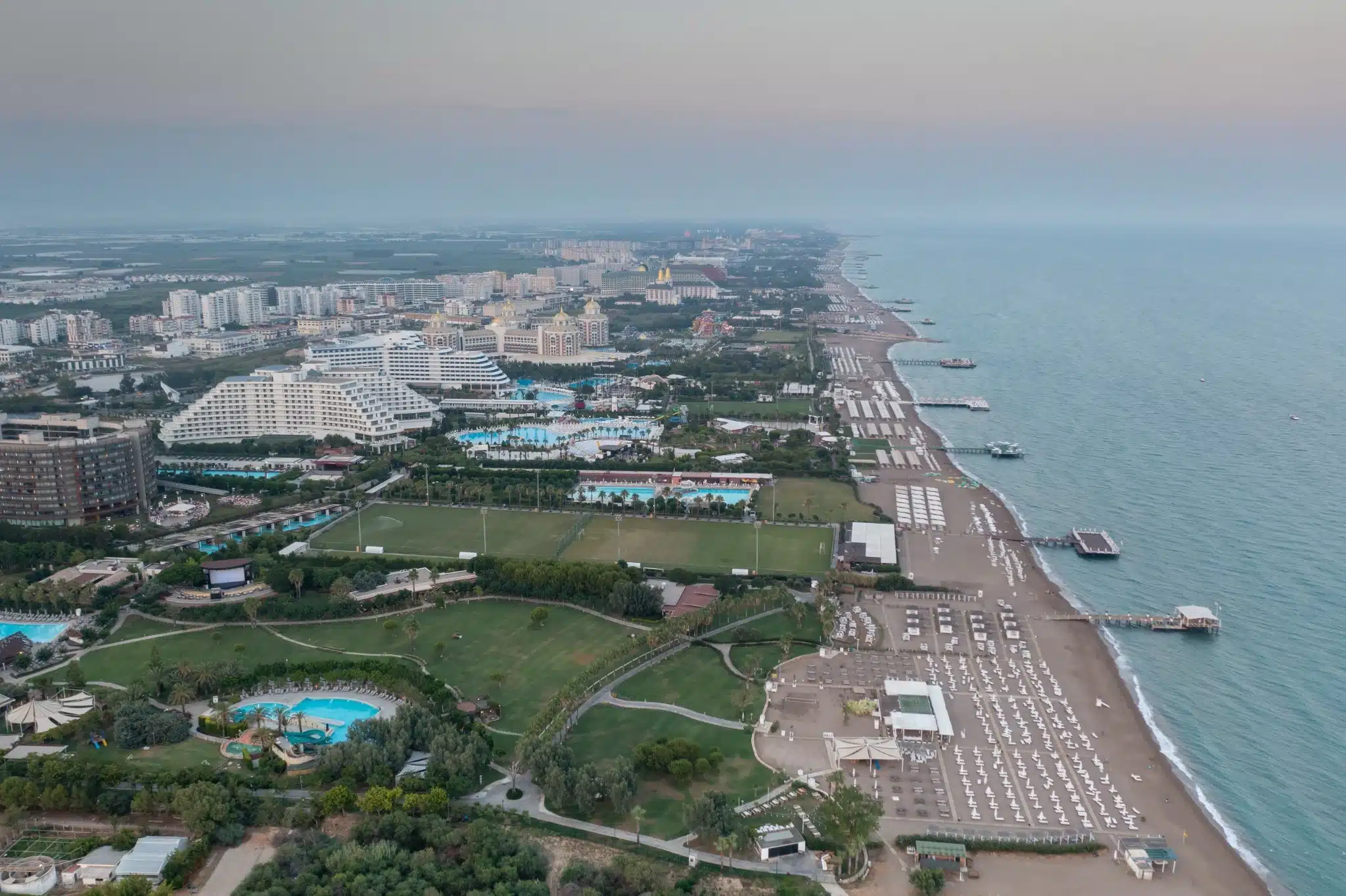 Luchtfoto van Lara Beach in Antalya, met luxe hotels, zwembaden en ligbedden langs de uitgestrekte kustlijn aan de Middellandse Zee.