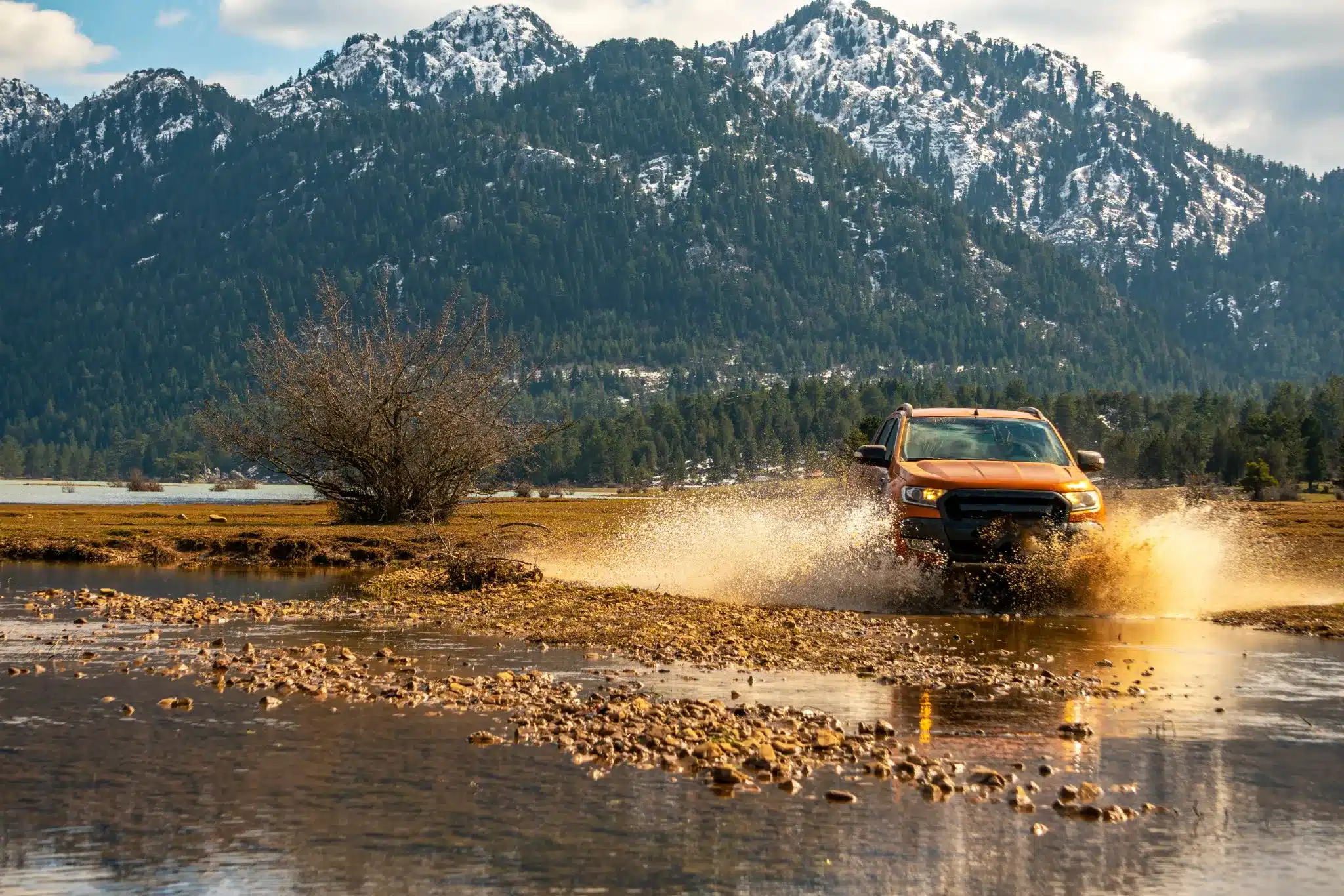 Oranje jeep rijdt door een waterplas tijdens een avontuurlijke offroad jeepsafari in het Taurusgebergte, Antalya, Turkije.